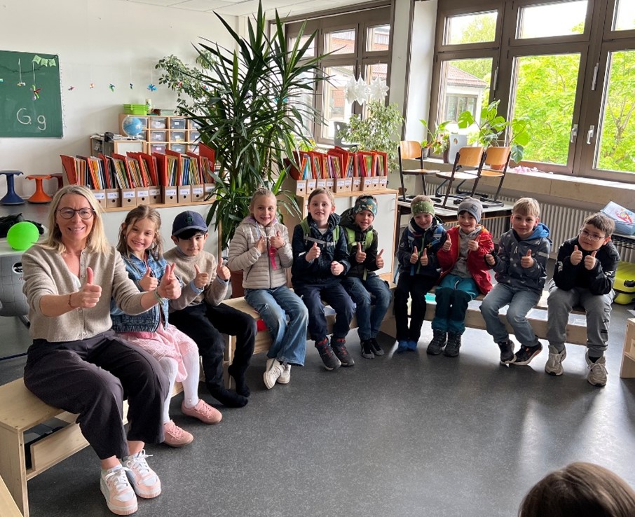 Eine Frau und viele Kinder sitzen auf Bänken