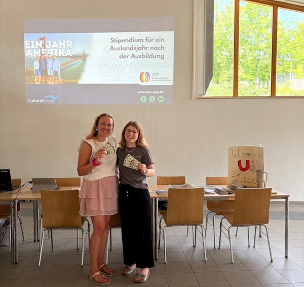 Zwei junge Frauen vor einer Powerpoint-Präsentation mit Geldscheinen in der Hand